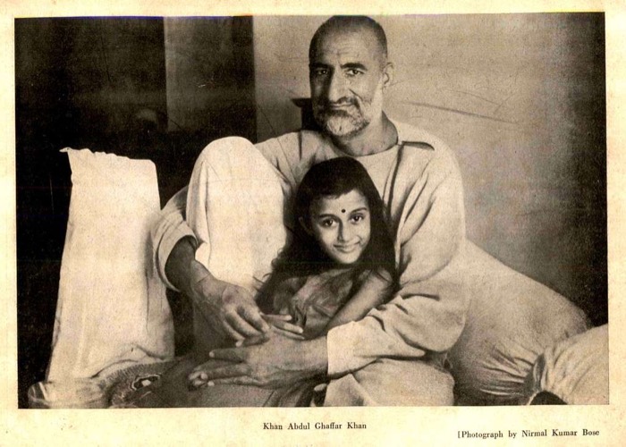 Printed archival plate showing Ghaffar Khan reclining against bolsters with a young girl seated in front of him, both facing the camera, with a printed caption beneath.